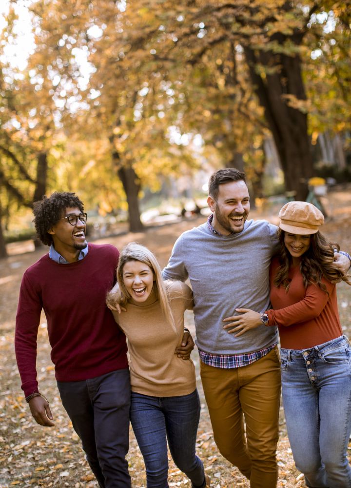 Quatre amis qui se promènent en riant dans un parc en automne